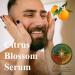 A man with his face being caressed with orange blossoms and a tangerine in the 
