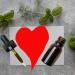 a red heart drawn between a glass dropper and bottle, surrounded by herbs