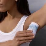 Applying a stick deodorant to an armpit