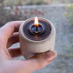 Candle: Beeswax Tealight With Cup in Black in a hand