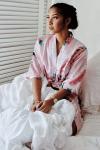 woman_in_white_and_pink_floral_robe_sitting_on_bed-scopio-4x6